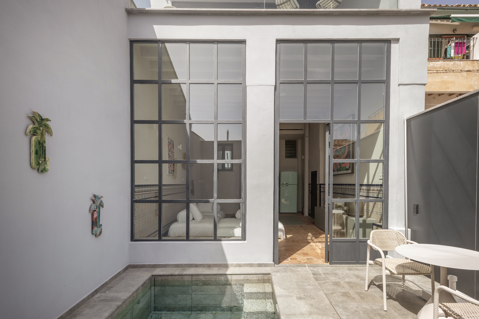 Kleiner Innenhof mit Pool, Sitzbereich und Blick in modernes Wohnzimmer mit französischen Fenstern.